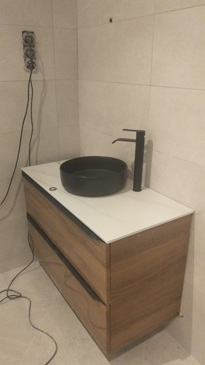 Mueble de baño suspendido con encimera de mármol y lavabo negro sobre encimera